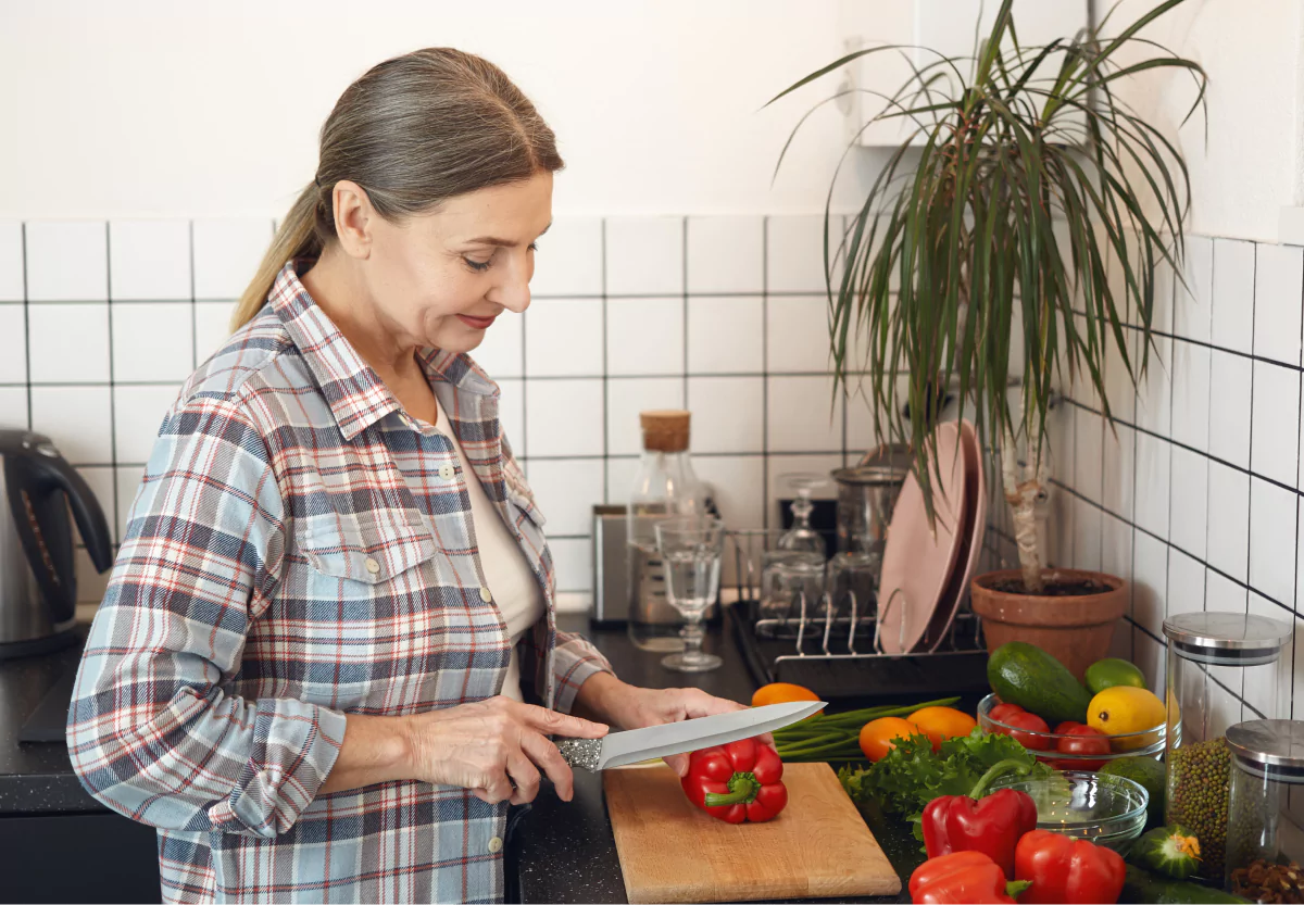 a woman chopping a red bell pepper
